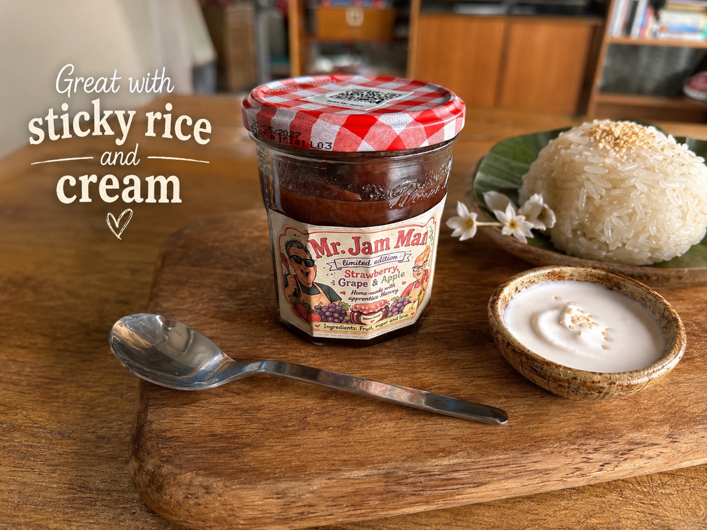 A jar of Mr. Jam Man jam on a wooden board next to a mound of sticky rice on a banana leaf and a small bowl of coconut cream, with the words Great with sticky rice and cream